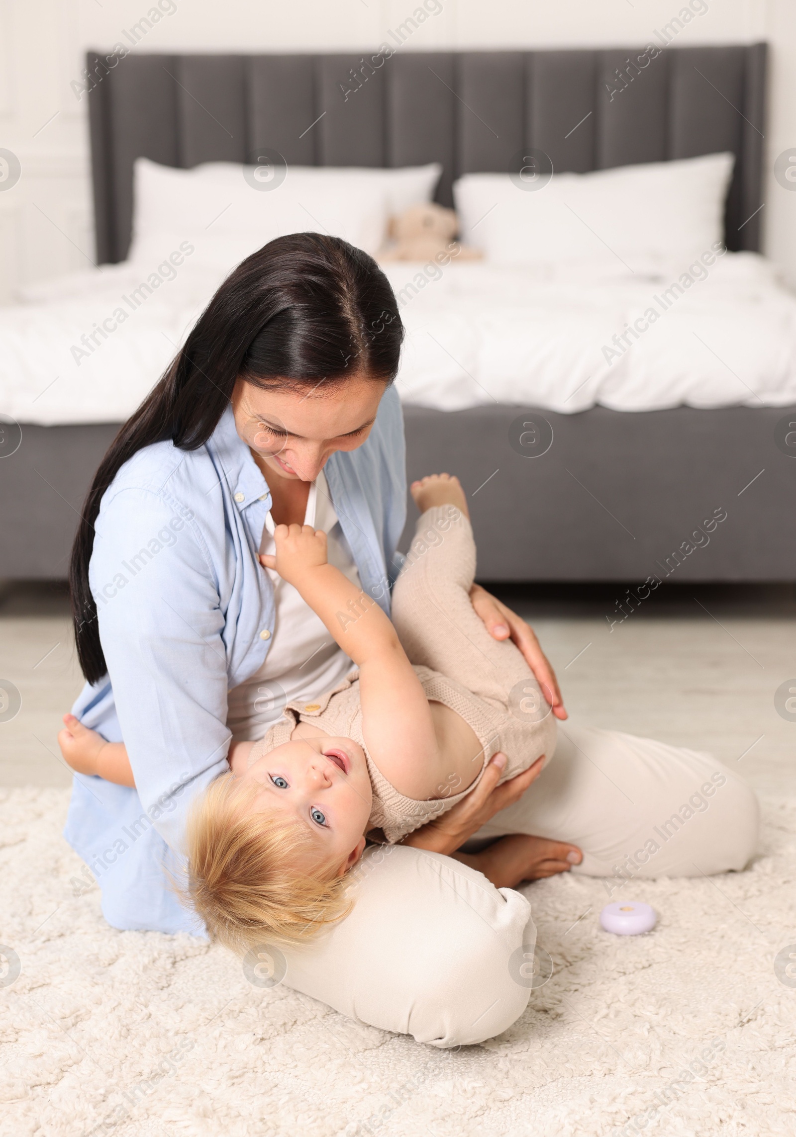 Photo of Mother playing with her cute baby on floor in bedroom