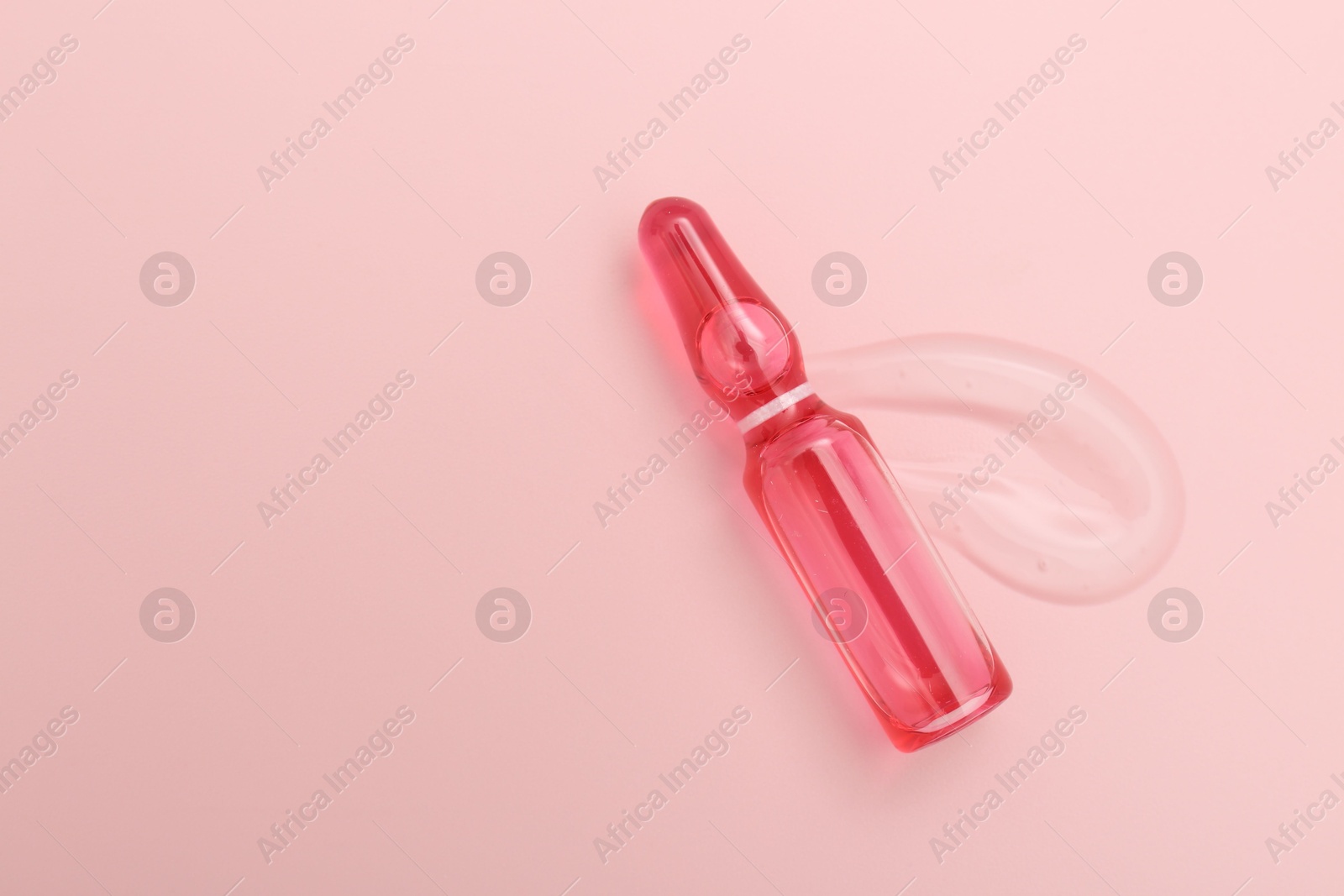 Glass ampoule with cosmetic product on pink background, top view. Space for text Photo of Glass ampoule with cosmetic product on pink background, top view. Space for text