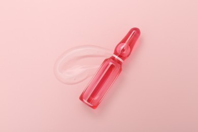 Photo of Glass ampoule with cosmetic product on pink background, top view