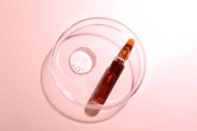 Photo of Glass ampoule with cosmetic product and Petri dish on pink background, top view
