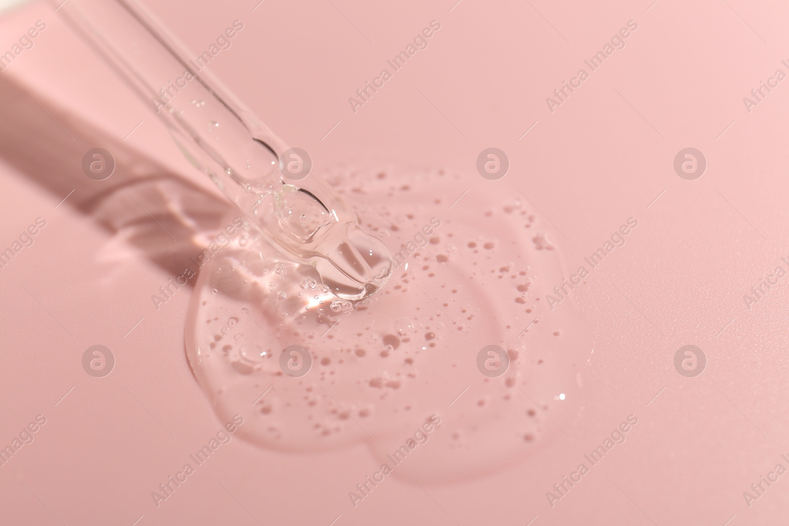 Dripping cosmetic product from pipette on pink background, closeup Photo of Dripping cosmetic product from pipette on pink background, closeup