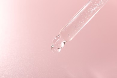 Photo of Dripping cosmetic product from pipette on pink background, closeup. Space for text