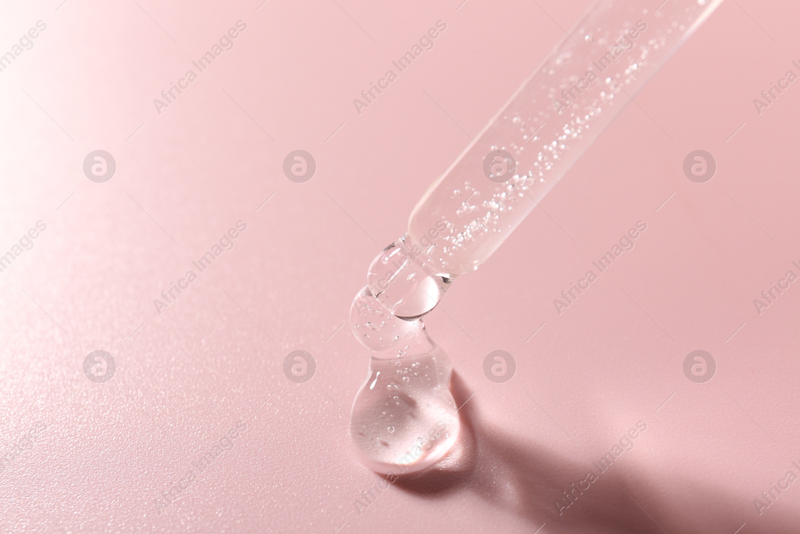 Dripping cosmetic product from pipette on pink background, closeup. Space for text Photo of Dripping cosmetic product from pipette on pink background, closeup. Space for text