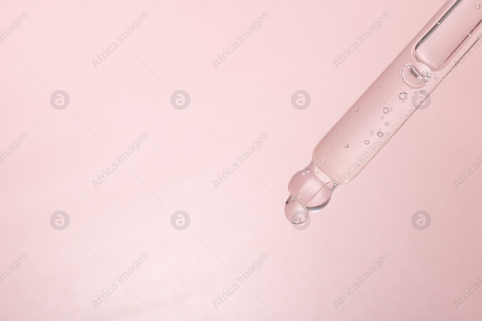 Dripping cosmetic product from pipette on pink background, closeup. Space for text Photo of Dripping cosmetic product from pipette on pink background, closeup. Space for text