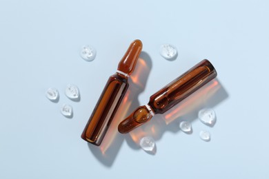 Photo of Glass ampoules with cosmetic product on light blue background, flat lay