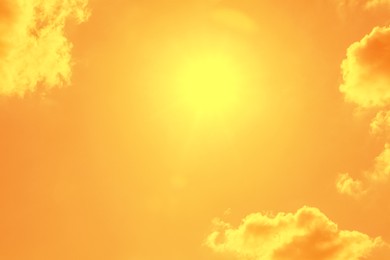Image of Bright sun and clouds in orange sky during hot summer weather