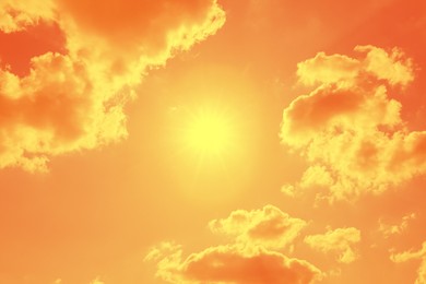 Image of Bright sun and clouds in orange sky during hot summer weather