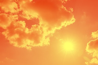 Image of Bright sun and clouds in orange sky during hot summer weather