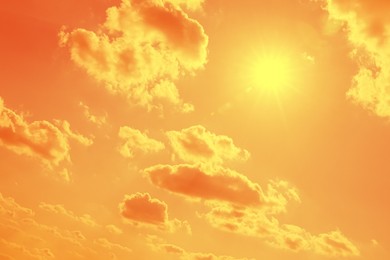 Image of Bright sun and clouds in orange sky during hot summer weather