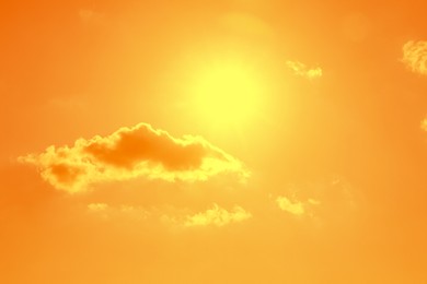 Image of Bright sun and clouds in orange sky during hot summer weather