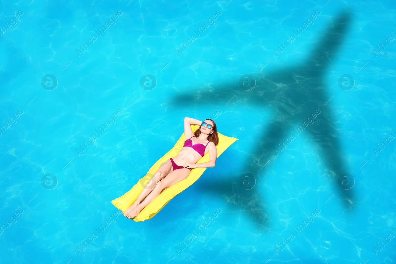 Young woman on inflatable mattress in swimming pool, above view. Flying airplane casting shadow on water Image of Young woman on inflatable mattress in swimming pool, above view. Flying airplane casting shadow on water