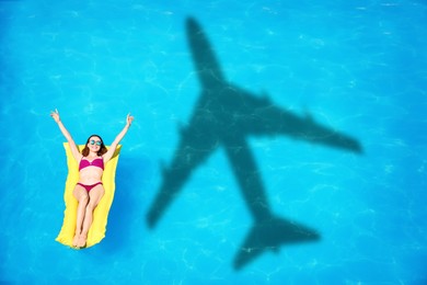 Image of Young woman on inflatable mattress in swimming pool, above view. Flying airplane casting shadow on water