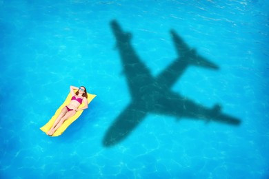 Image of Young woman on inflatable mattress in swimming pool, above view. Flying airplane casting shadow on water