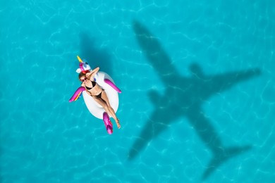 Image of Young woman with inflatable ring in swimming pool, above view. Flying airplane casting shadow on water