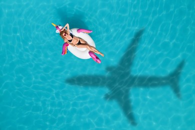 Image of Young happy woman with inflatable ring in swimming pool, above view. Flying airplane casting shadow on water