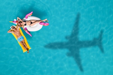 Image of Happy couple with inflatable ring and mattress in swimming pool, top view. Flying airplane casting shadow on water