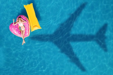 Image of Happy woman with inflatable mattress and ring in swimming pool, top view. Flying airplane casting shadow on water