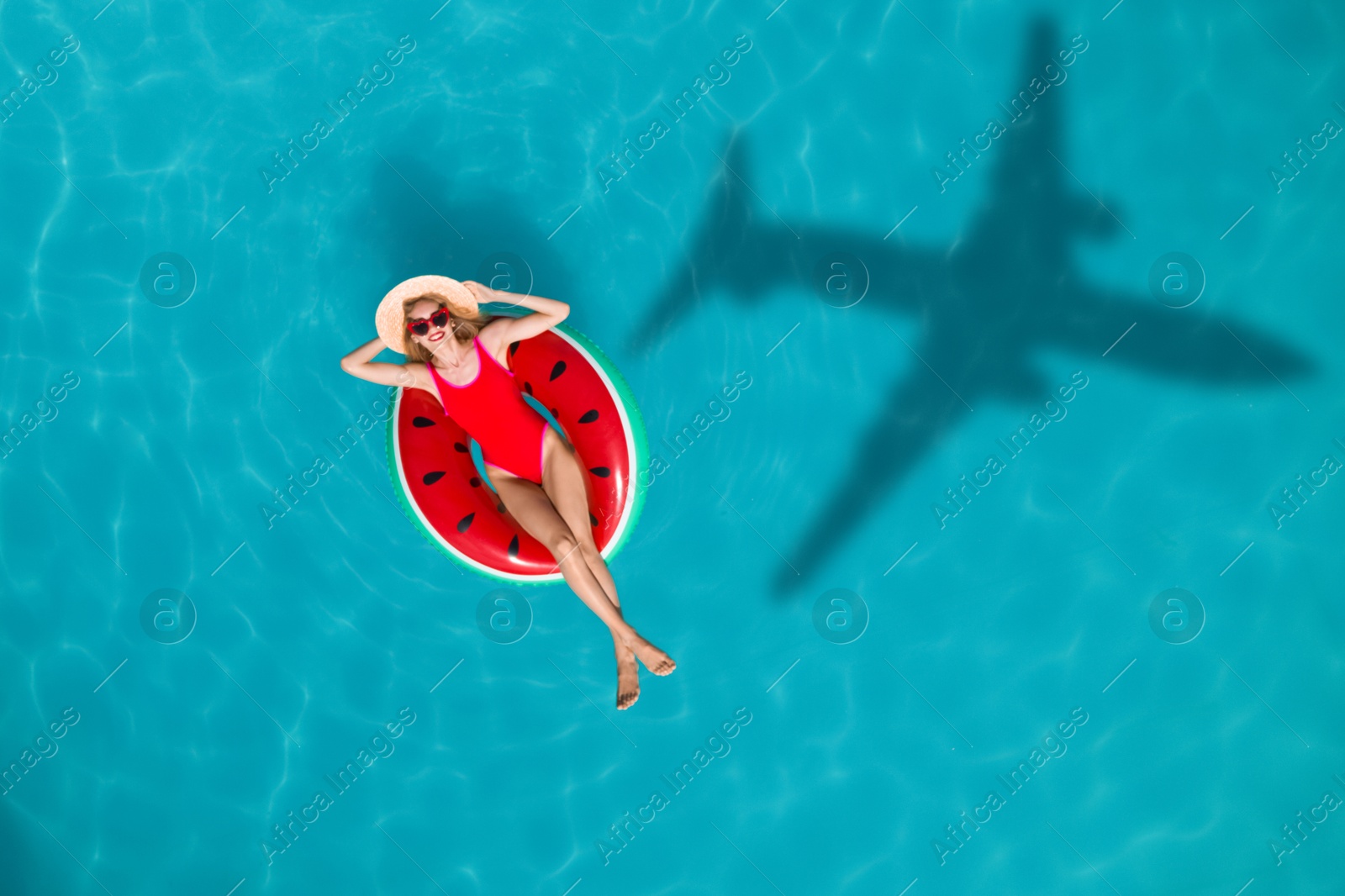 Image of Young happy woman with inflatable ring in swimming pool, top view. Flying airplane casting shadow on water