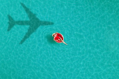 Image of Young happy woman with inflatable ring in swimming pool, top view. Flying airplane casting shadow on water
