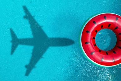 Image of Inflatable ring floating in swimming pool, top view. Flying airplane casting shadow on water