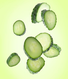 Image of Pieces of fresh cucumbers falling on green gradient background