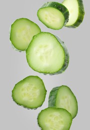 Image of Pieces of fresh cucumbers falling on grey background