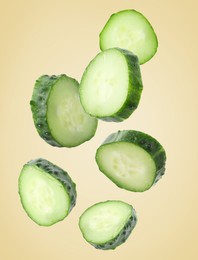 Image of Pieces of fresh cucumbers falling on beige gradient background