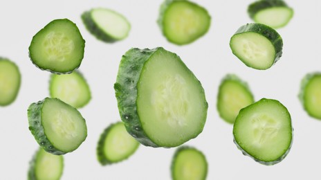 Image of Pieces of fresh cucumbers falling on light background