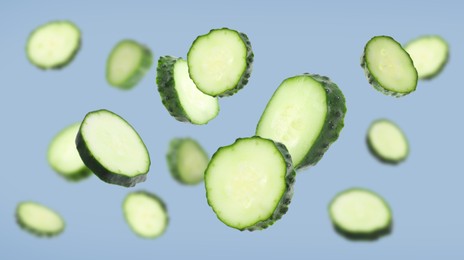 Image of Pieces of fresh cucumbers falling on greyish blue background