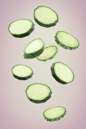 Image of Pieces of fresh cucumbers falling on color gradient background