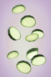 Image of Pieces of fresh cucumbers falling on color gradient background