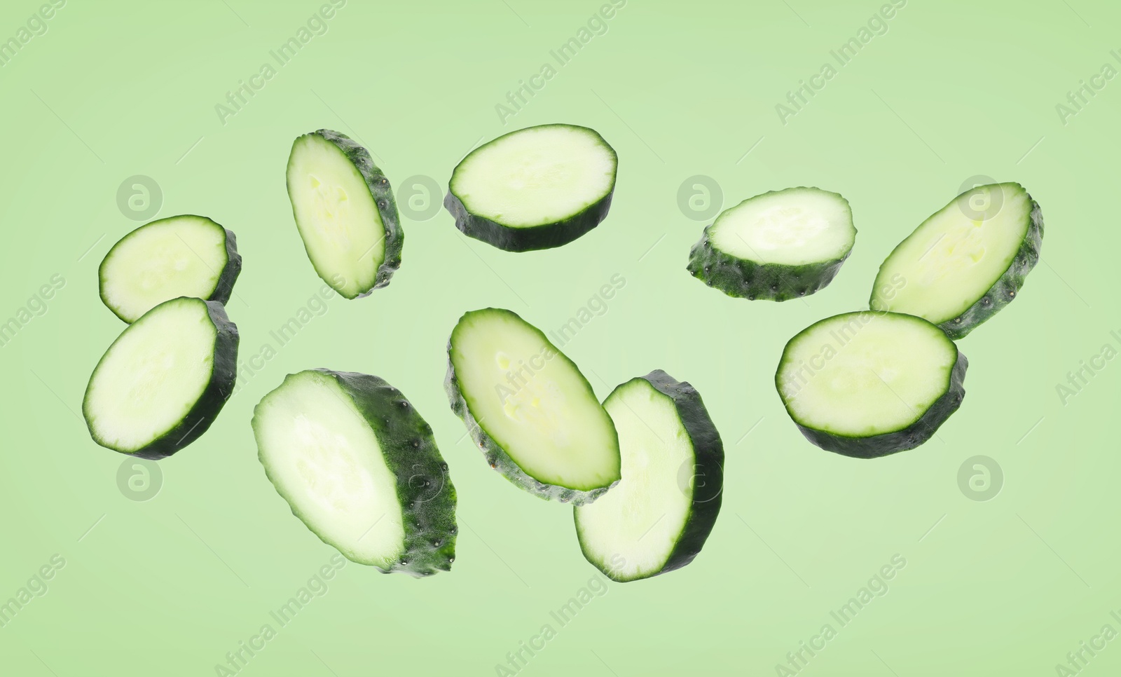 Pieces of fresh cucumbers falling on green background Image of Pieces of fresh cucumbers falling on green background