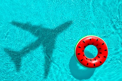 Image of Inflatable ring floating in swimming pool, top view. Flying airplane casting shadow on water