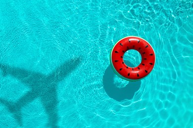 Image of Inflatable ring floating in swimming pool, top view. Flying airplane casting shadow on water