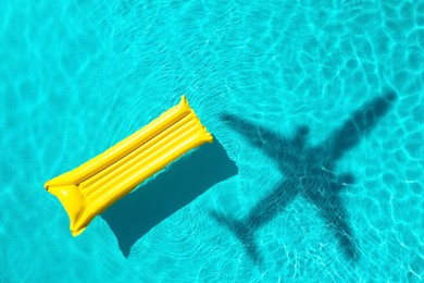 Image of Inflatable mattress floating in swimming pool, top view. Flying airplane casting shadow on water