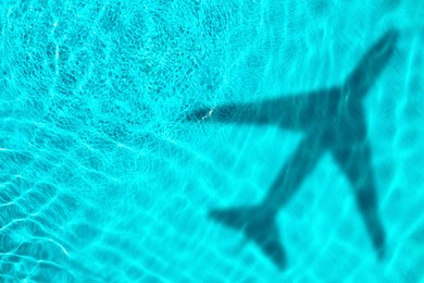 Image of Flying airplane casting shadow on water, top view