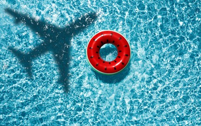 Image of Inflatable ring floating in swimming pool, top view. Flying airplane casting shadow on water