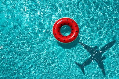 Image of Inflatable ring floating in swimming pool, top view. Flying airplane casting shadow on water