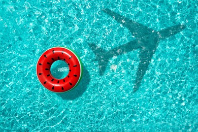 Image of Inflatable ring floating in swimming pool, top view. Flying airplane casting shadow on water