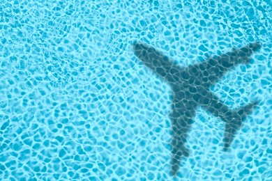 Image of Flying airplane casting shadow on water, top view