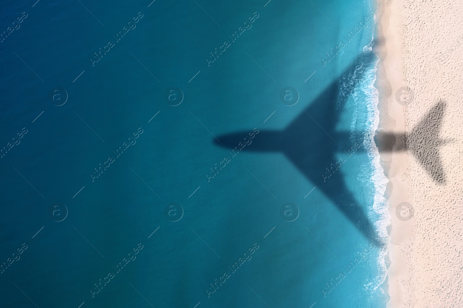 Flying airplane casting shadow on sandy beach and water, top view Image of Flying airplane casting shadow on sandy beach and water, top view
