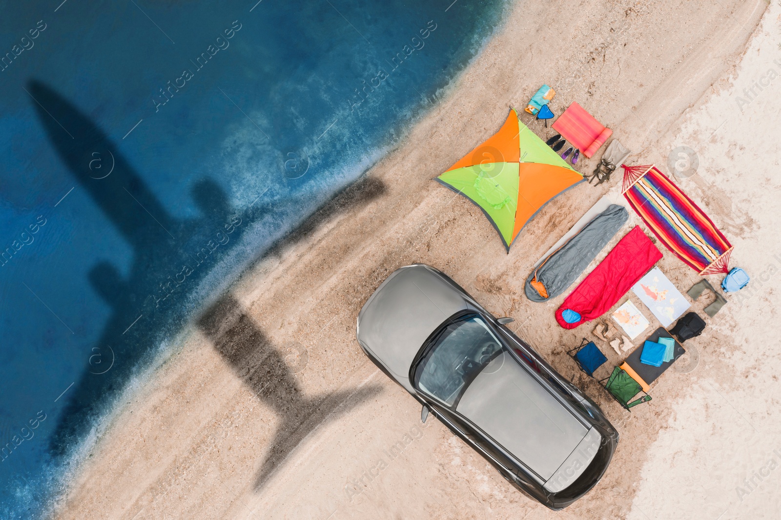 Car and camping equipment on beach. Flying airplane casting shadow on sand and water Image of Car and camping equipment on beach. Flying airplane casting shadow on sand and water