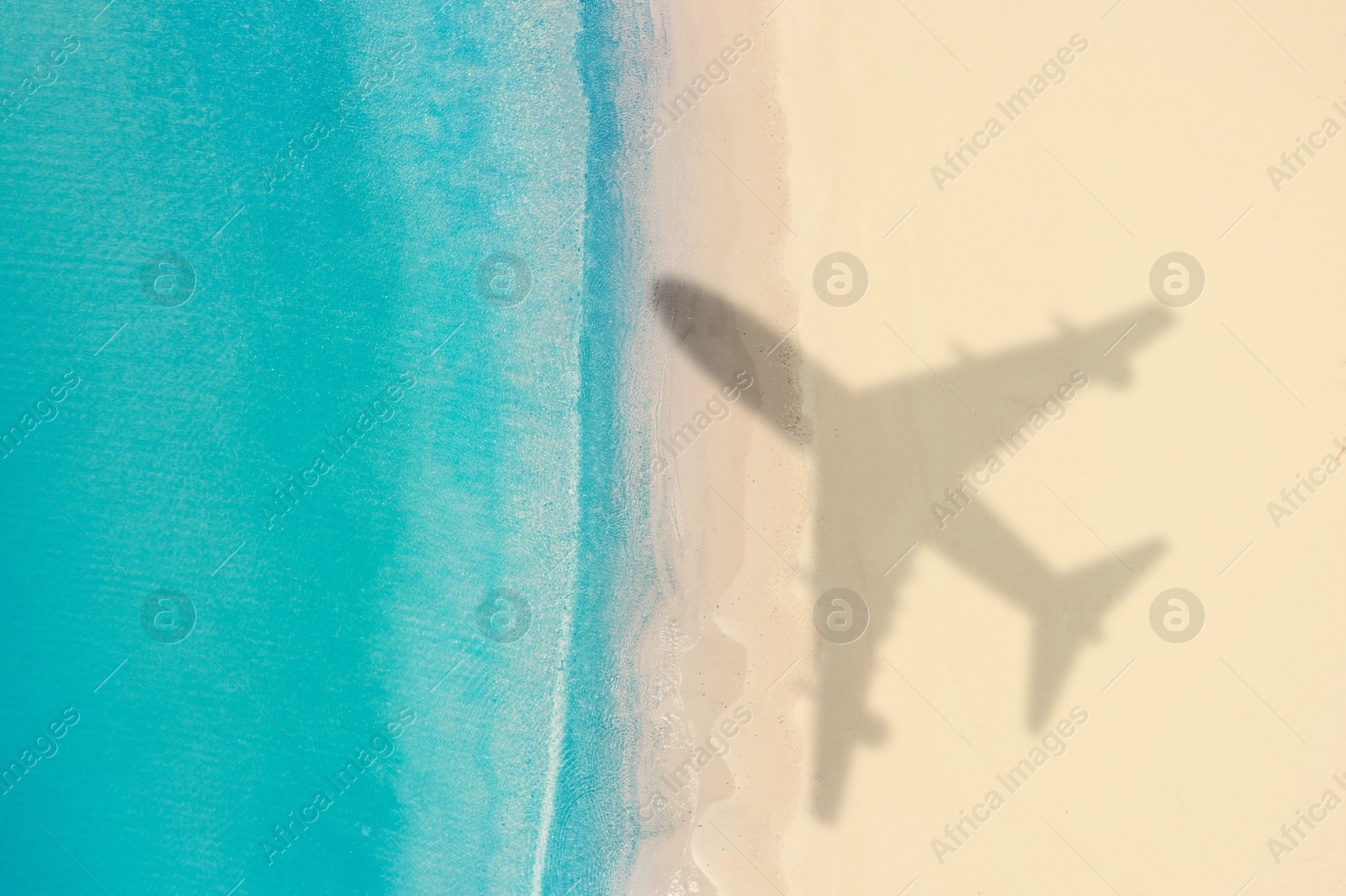 Image of Flying airplane casting shadow on sandy beach, top view
