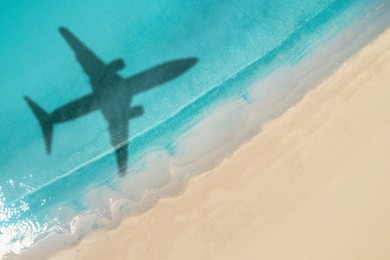 Image of Flying airplane casting shadow on water, top view
