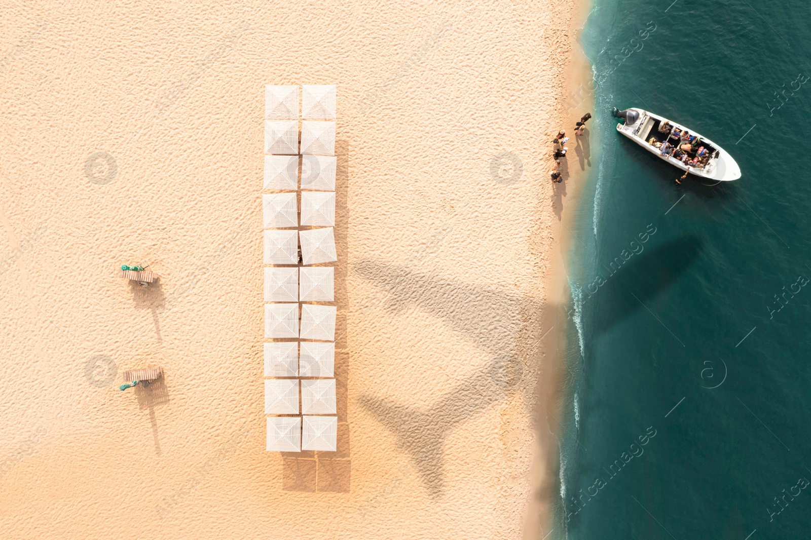 Motorboat near coast with beach umbrellas, top view. Flying airplane casting shadow on sand and water Image of Motorboat near coast with beach umbrellas, top view. Flying airplane casting shadow on sand and water