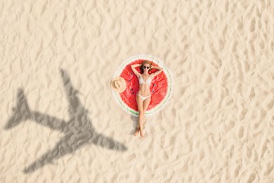 Image of Woman sunbathing on beach, top view. Flying airplane casting shadow on sand