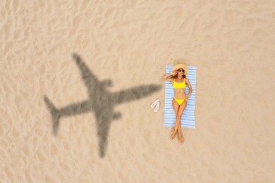 Image of Woman sunbathing on beach, top view. Flying airplane casting shadow on sand