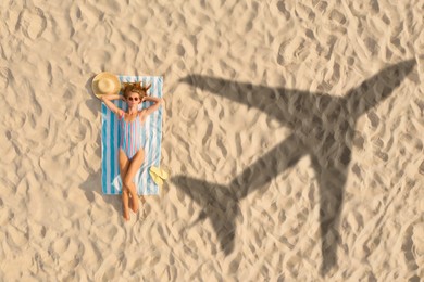 Image of Woman sunbathing on beach, top view. Flying airplane casting shadow on sand