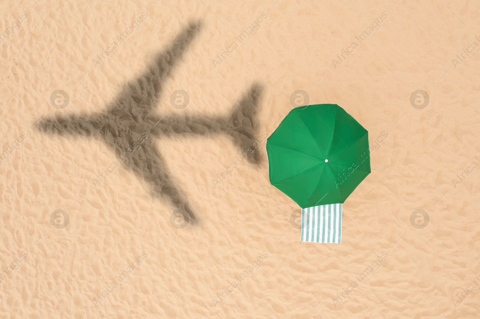 Green umbrella and striped towel on beach, top view. Flying airplane casting shadow on sand Image of Green umbrella and striped towel on beach, top view. Flying airplane casting shadow on sand