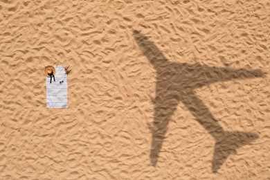 Image of Vacationer's stuff on beach, top view. Flying airplane casting shadow on sand
